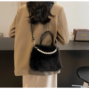 Dettaglio borsa a secchiello in peluche nera con manico di perle e finiture oro