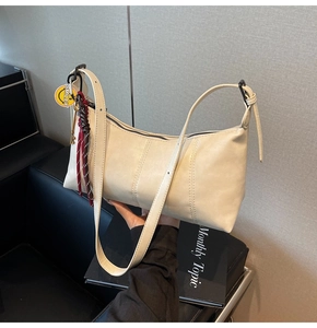 Detail of off-white shoulder bag with stitching, Smiley charm and woven rope knot