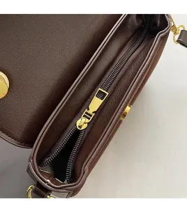 Detail of smooth gold zipper and texture on a brown leather crossbody bag