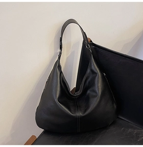 Detailansicht der großen schwarzen Hobo-Tasche aus genarbtem Leder auf einem Stuhl