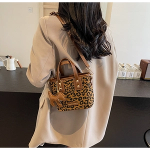 Détail du sac seau léopard avec poignées en cuir contrasté et pendentif chien