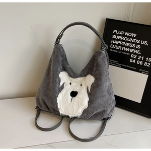Detail of grey corduroy hobo bag featuring a plush white dog applique with silver hardware
