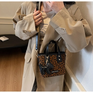 Détail du sac seau léopard avec breloque chien noir et logo métallique élégant