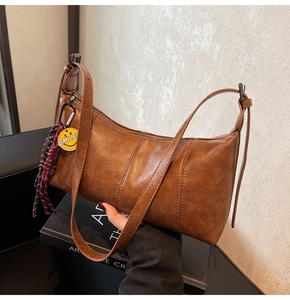 Close-up of brown vintage PU leather bag with smiley charm and top zipper detail