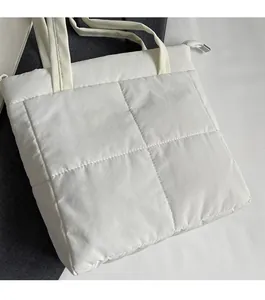 Detail shot of the cream white quilted fabric bag featuring a zipper and soft puffer texture