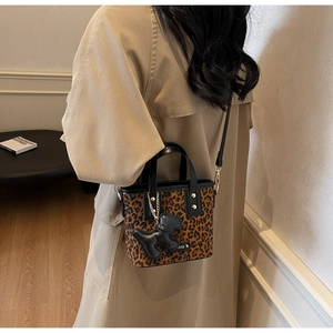 Détail du sac seau léopard avec bordure en cuir noir et breloque chiot sur modèle