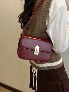 Retro burgundy shoulder bag with gold metal buckle worn by a model in a preppy style outfit