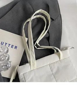 Detail of white quilted nylon shoulder bag showing puffy texture and sturdy straps