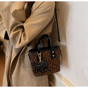 Détail du sac seau léopard avec logo métallique et breloque chien sur trench-coat beige