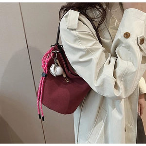 Burgunderrote Wildleder-Eimertasche mit Baseball-Anhänger und rosa geflochtenem Kordelzug