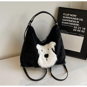 Detail shot of black corduroy tote bag featuring a large white plush puppy patch