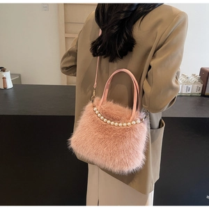 Dettaglio della borsa a secchiello in peluche rosa con catena di perle e morbida pelliccia