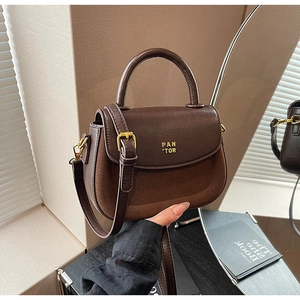 Close-up of brown patchwork handbag featuring suede leather texture and gold hardware