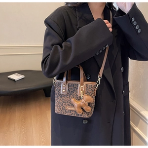 Détail d'un sac seau léopard en toile avec bordures en cuir et charm chien fantaisie
