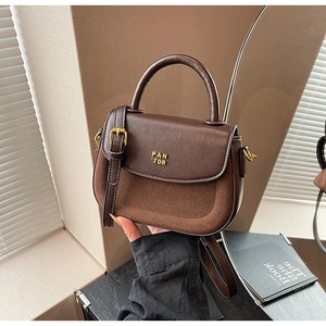 Detail of a dark brown handbag featuring contrasting smooth leather and suede textures