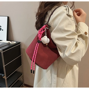 Detail der burgunderroten Matt-Schultertasche mit rosa Seil und weißem Anhänger