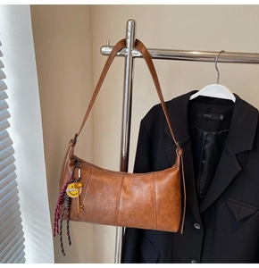 Detail of a brown vintage baguette bag with Smiley charms hanging on a metal rack