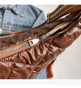 Close-up of smooth silver zipper and quilted puffer fabric on a brown crossbody bag