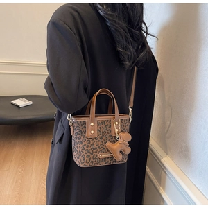 Sac seau chic à imprimé léopard avec breloque ours porté avec élégance par un mannequin