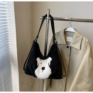 Close-up of black corduroy tote featuring a plush schnauzer dog patch and leather straps