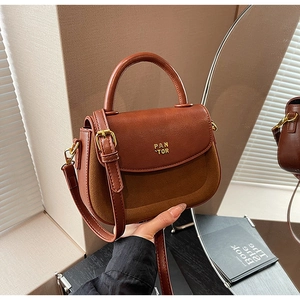 Macro detail of brown leather patchwork handbag featuring gold PAN TOR metal lettering