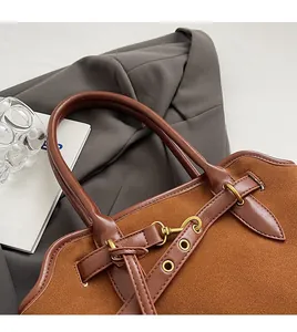 Detail der karamellfarbenen Wildledertasche mit Metallschnalle und Ledergriff