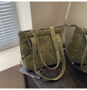 Detail shot of army green quilted nylon fabric and dual handle straps on the tote bag