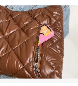 Detailed close-up of the side zipper pocket on a brown quilted puffer shoulder bag