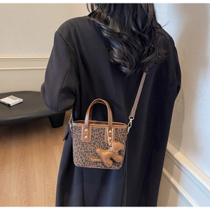 Détail du sac léopard avec poignée en cuir marron et charmant pendentif d'ours brun