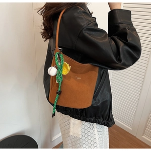Detail der braunen Wildleder-Eimertasche mit Logo und bunten Taschenanhängern