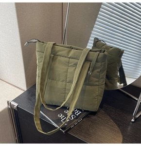 Detailed view of olive green quilted puffer tote bag on a black wooden surface