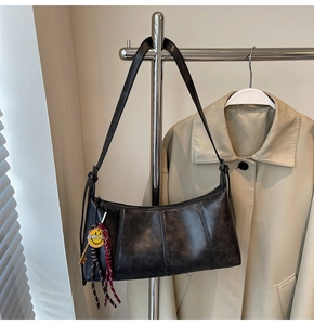 Detail of vintage black faux leather underarm bag with smile pendant on a metal hanger