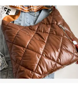 Close-up of brown quilted puffer shoulder bag with stylish patterned woven strap