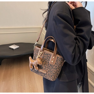 Sac seau à motif léopard avec poignées brunes et charme de chiot sur un mannequin
