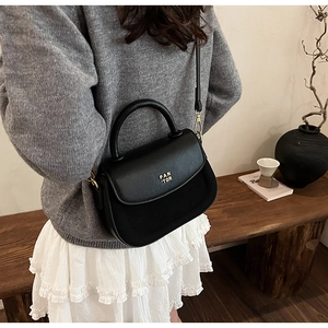 Detail shot of black leather saddle bag with gold logo and elegant gold hardware accents
