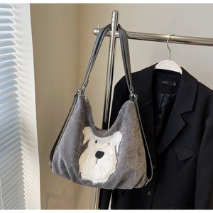 Detail of grey corduroy hobo bag featuring a plush white dog embroidery and grey straps