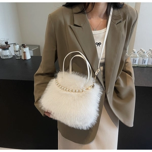Dettaglio borsa a secchiello in peluche bianco con manico di perle su blazer marrone
