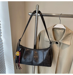 Detailed view of black underarm bag with vertical stitching and smile charm