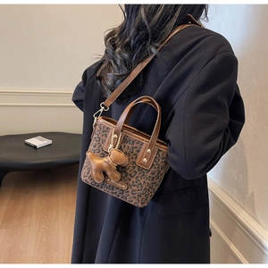 Détail du sac seau léopard avec breloque ours en cuir et logo métallique de marque