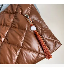 Close-up of brown quilted shoulder bag featuring a decorative flower tassel pendant