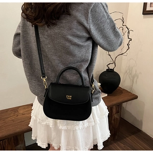Close-up of black matte handbag with gold PAN 'TOR logo and structured handle