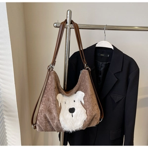 Detail of brown corduroy hobo tote bag featuring a fluffy white plush dog applique