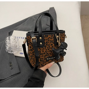 Détail d'un mini tote bag imprimé léopard avec bordures cuir et breloque animal