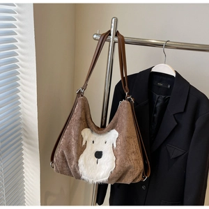 Detail of brown corduroy tote bag featuring a cute white plush dog patch and leather handles