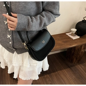 Detail of a black leather saddle bag with a gold PAN'TOR logo on a half-round flap