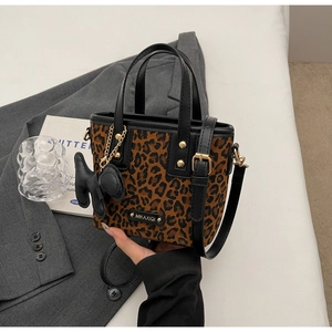 Détail d'un sac cabas léopard avec poignée en cuir noir et charm en forme de chien