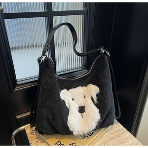 Detail of black corduroy tote bag with white plush puppy patch and adjustable leather strap