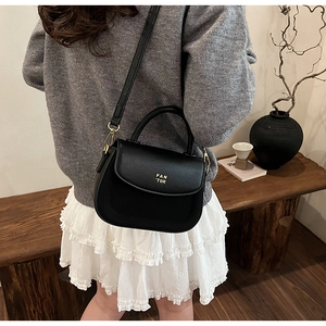 Detail of black leather saddle bag with gold Pan'Tor logo and elegant gold hardware