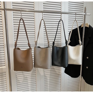 Detail view of stylish leather bucket bags with knot strap in brown, beige, black, and white