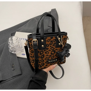 Détail du sac seau imprimé léopard avec bordure en cuir noir et breloque animal
